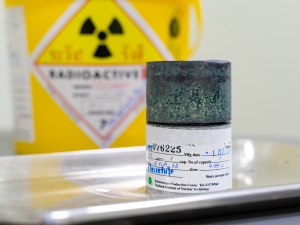 riscos químicos. Foto mostra uma placa de radioatividade no fundo e embalagem de produto químico a frente.